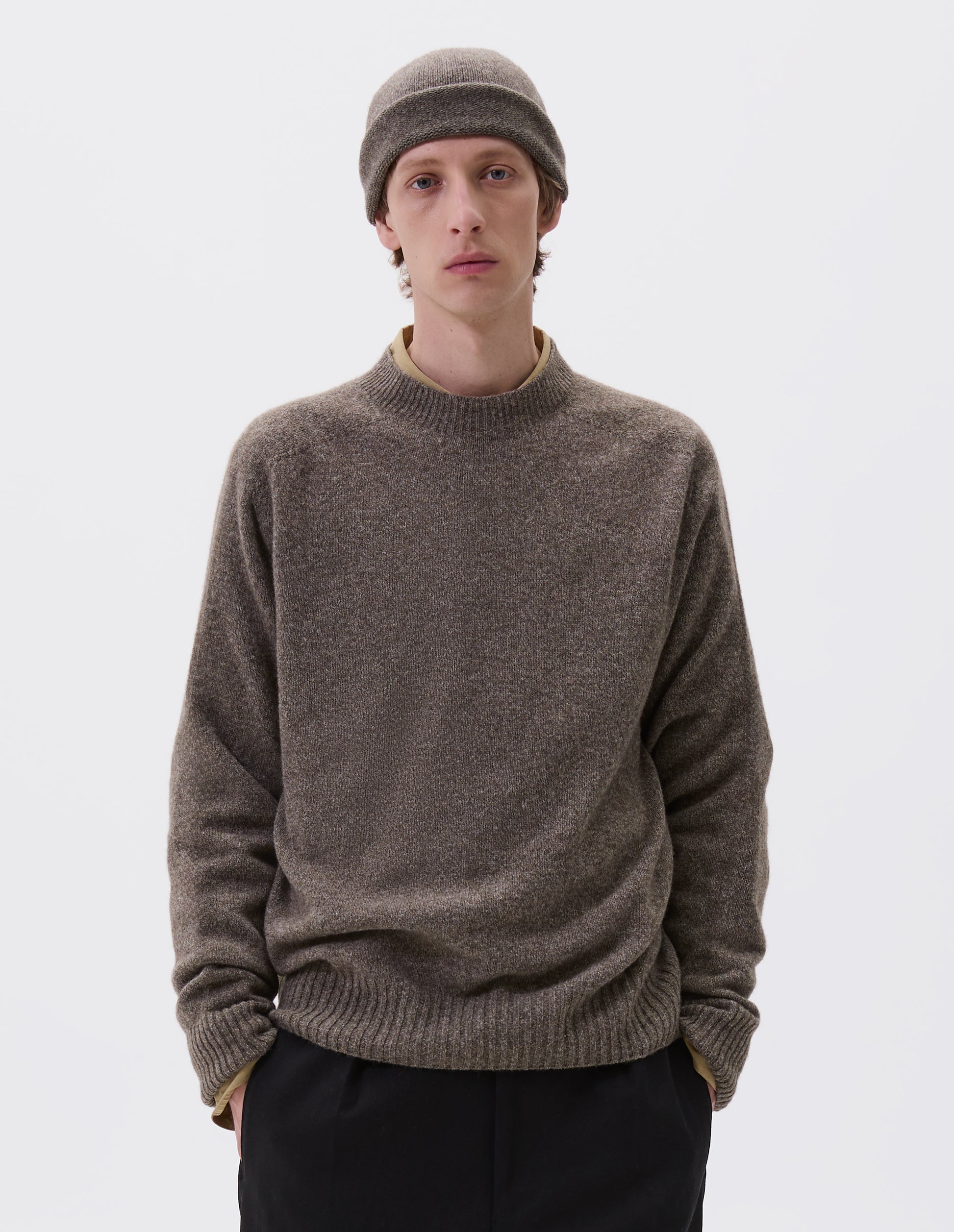 Cropped body image, front view of model wearing beige marl long sleeve jumper with contrast rib neckline, cuffs and hem. Styled over a yellow shirt, black trousers and with matching knitted hat.