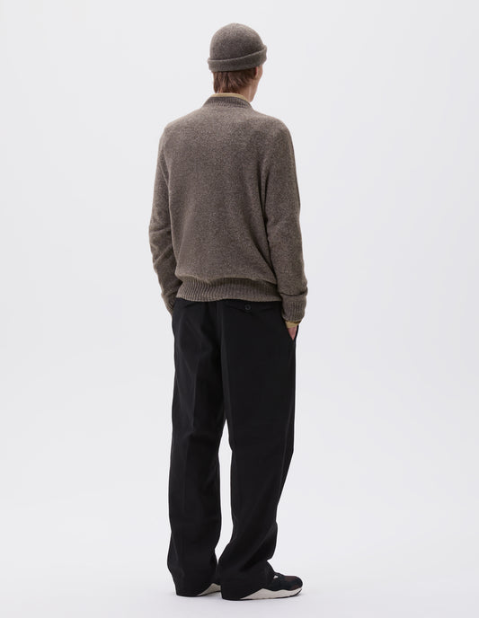 Full body image, back view of model wearing beige marl long sleeve jumper with contrast rib neckline, cuffs and hem. Styled over a yellow shirt, black trousers and with matching knitted hat.