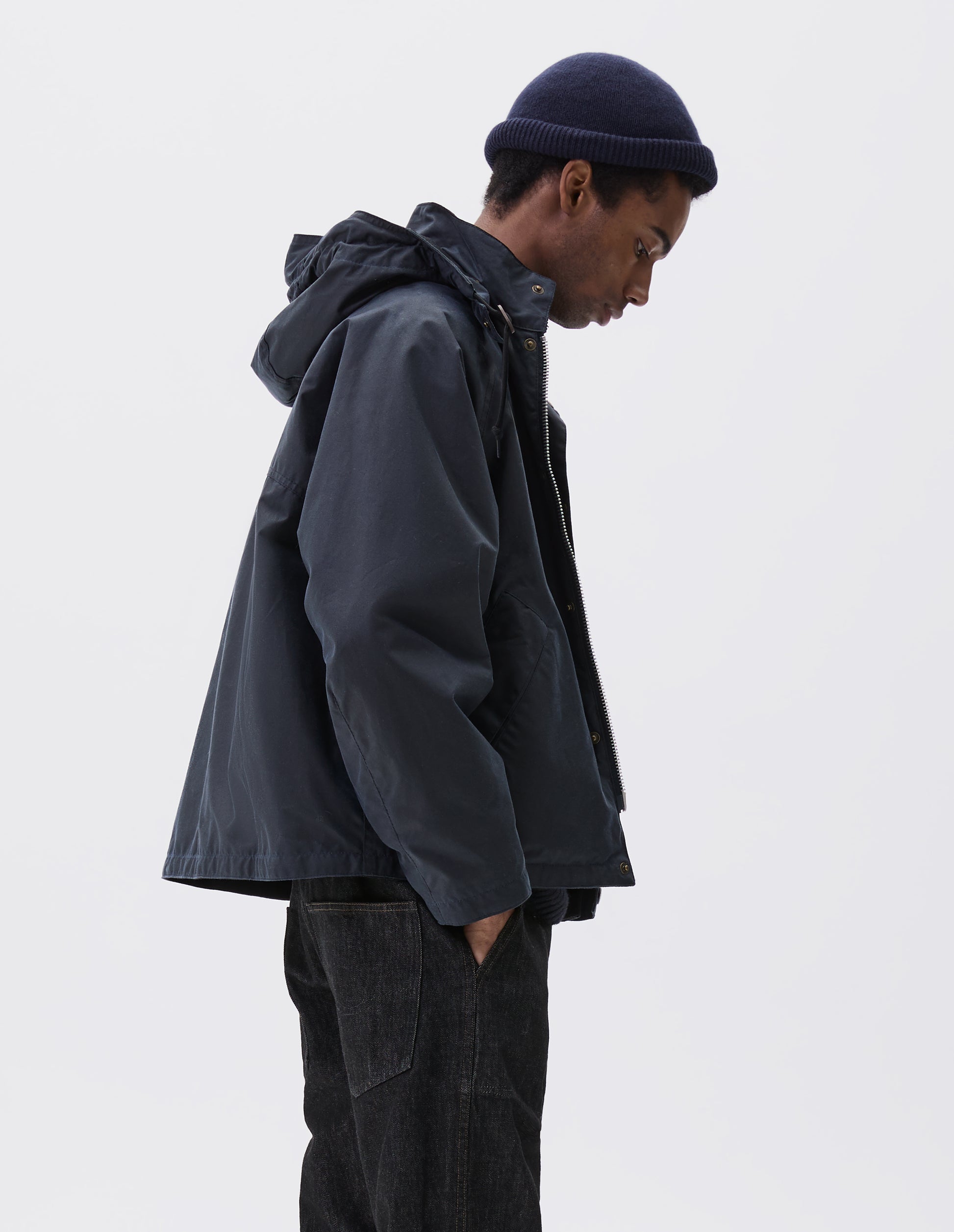 Cropped body image, side view of male model wearing navy blue cashmere beanie with contrast rib turn back rim rolled. Styled with navy blue waxed jacket and black denim jeans.