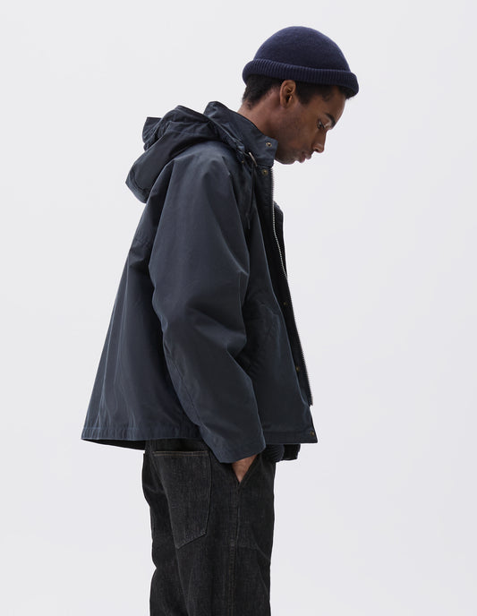 Cropped body image, side view of male model wearing navy blue cashmere beanie with contrast rib turn back rim rolled. Styled with navy blue waxed jacket and black denim jeans.