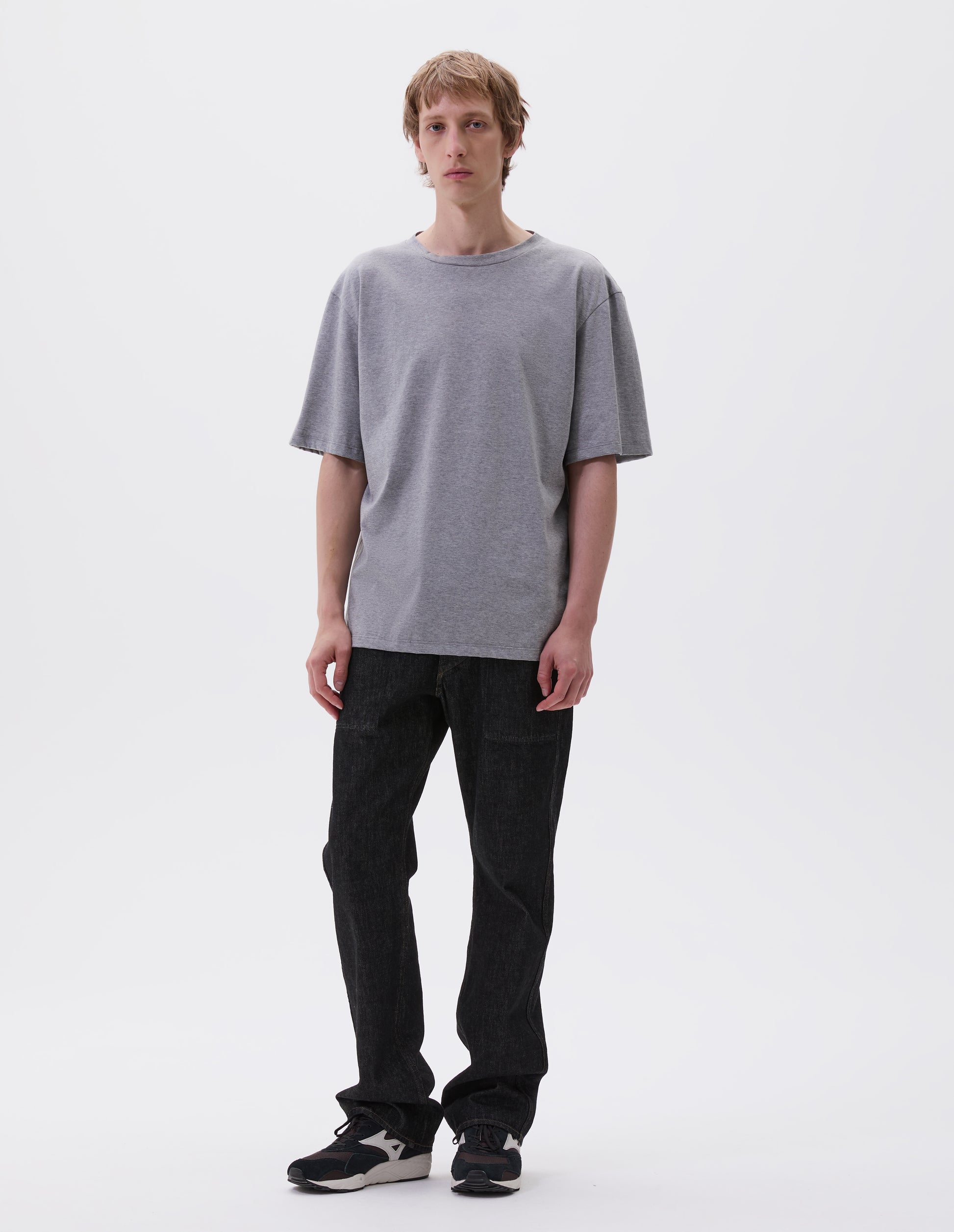 Full body image, front view with grey cotton short sleeve t-shirt. Styled with black denim jeans and black and brown trainers.