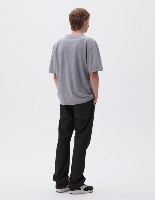Full body image, back view of model wearing grey cotton short sleeve t-shirt.  Styled with black denim jeans and black and brown trainers.