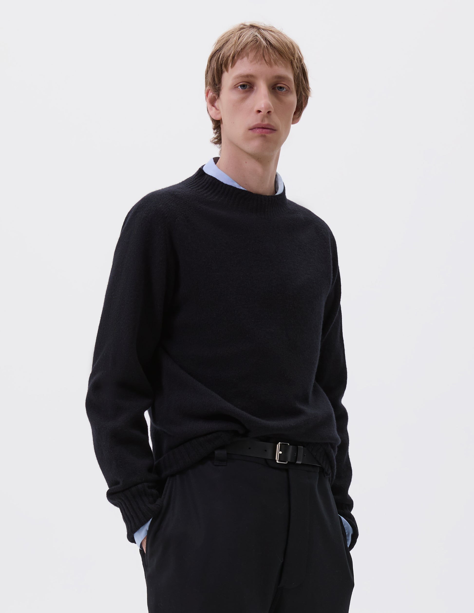 Cropped body image, front view of male model wearing black leather belt with silver buckle and black leather strap. Styled with blue shirt, dark navy jumper and navy trousers.