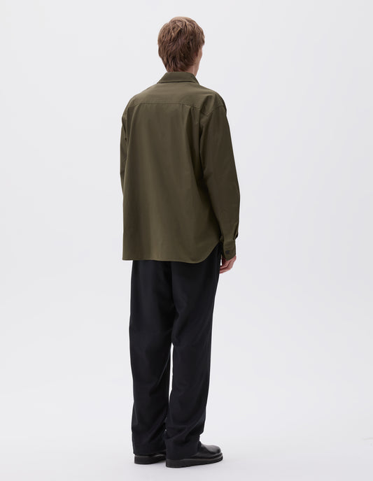 Full body image, back view of model wearing green shirt with with horn buttons on cuffs, styled with dark blue and black leather shoes. 