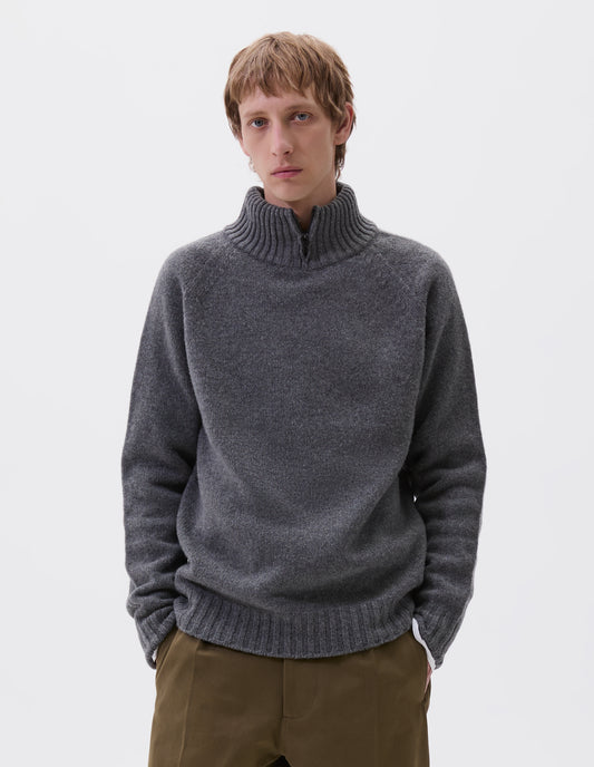 Cropped body image, front view of model wearing grey melange mock neck jumper with zip detailing, raglan sleeve and contrasting rib on neck, cuffs and hem. Styled with green trousers.