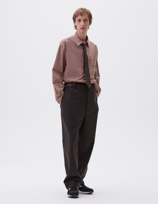 Full body image, front view of model wearing brown wool trousers, with half elasticated waistband, belt loops, horn button tab fastening and slant pockets. Styled with pink shirt, brown paisley tie, brown leather belt  and black and brown trainers.