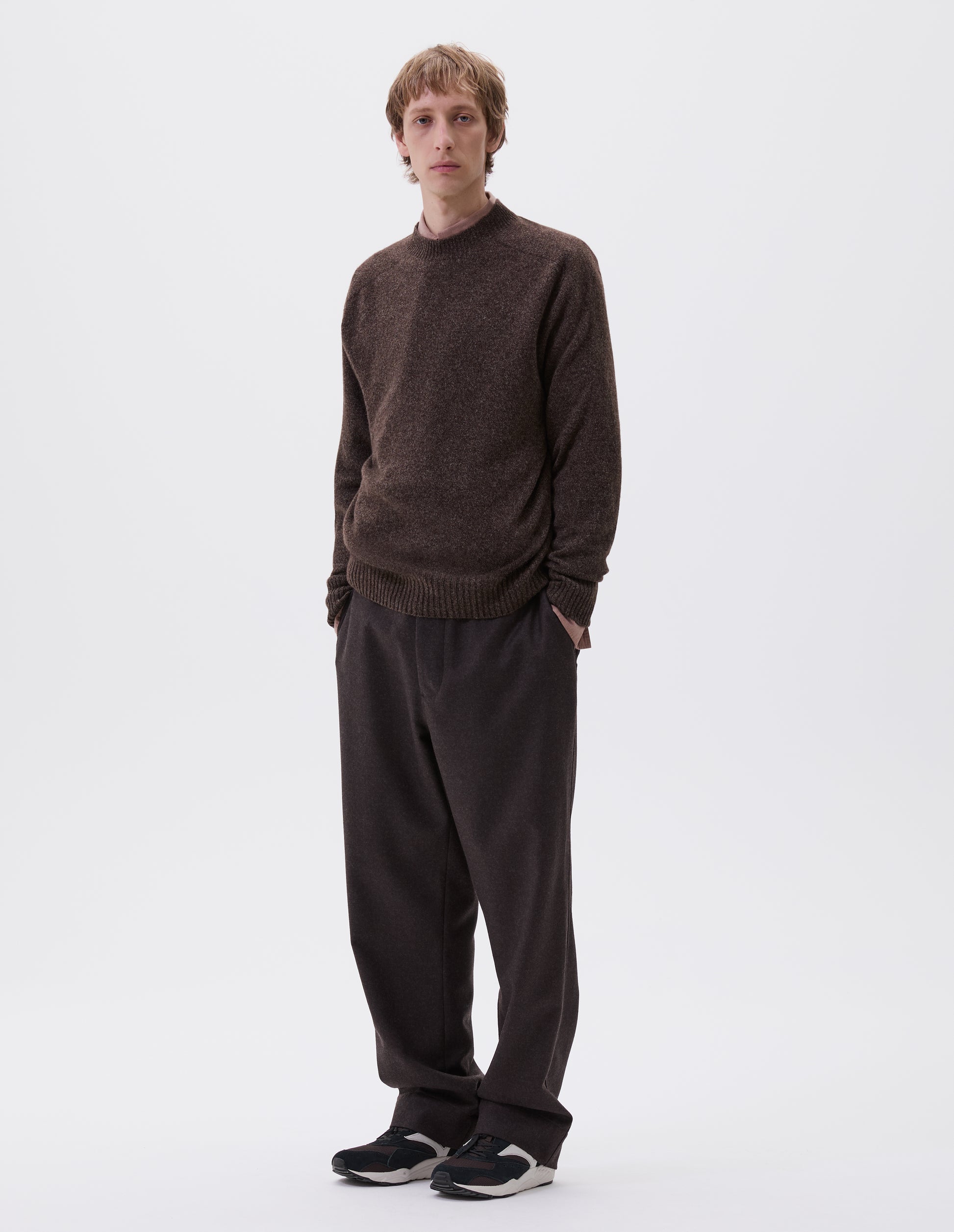 Full body image, front view of model wearing brown marl long sleeve jumper with contrast rib neckline, cuffs and hem. Styled with brown trousers, pink shirt and brown and black trainers.