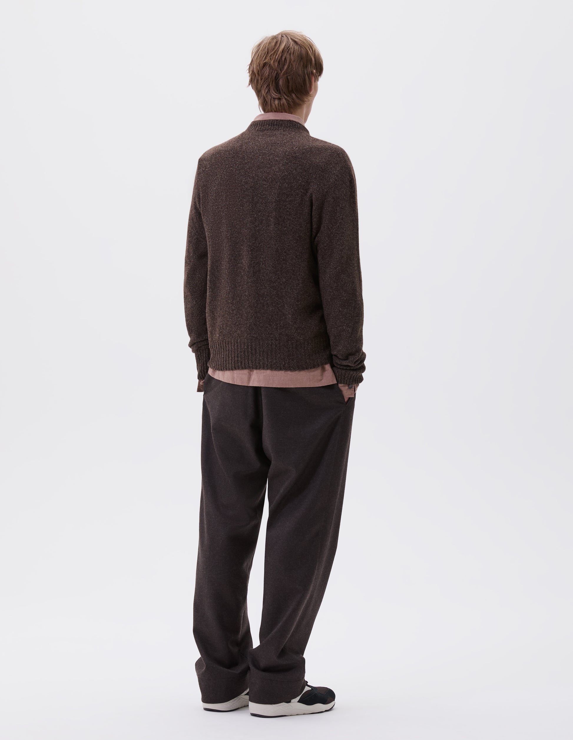 Full body image, back view of model wearing brown marl long sleeve jumper with contrast rib neckline, cuffs and hem. Styled with brown trousers, pink shirt and brown and black trainers.