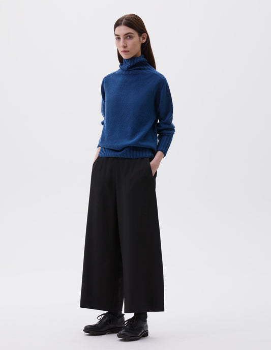 Full body image, front view of model wearing a pair of matt black leather brogues with black laces and lightweight rubber commando sole. Styled with blue high neck jumper and black culottes. 