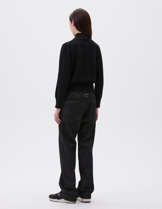 Full body image, back view of model wearing black mock neck cardigan with ribbed collar, cuffs and hem. Styled with black cinch back jeans, black leather belt and black, brown and white trainers.