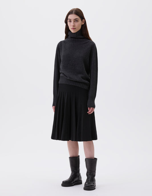 Full body image, front view of model wearing black leather three quarter length boots with Vibram sole and shearling lining. Styled with charcoal grey high neck jumper and black knitted skirt.