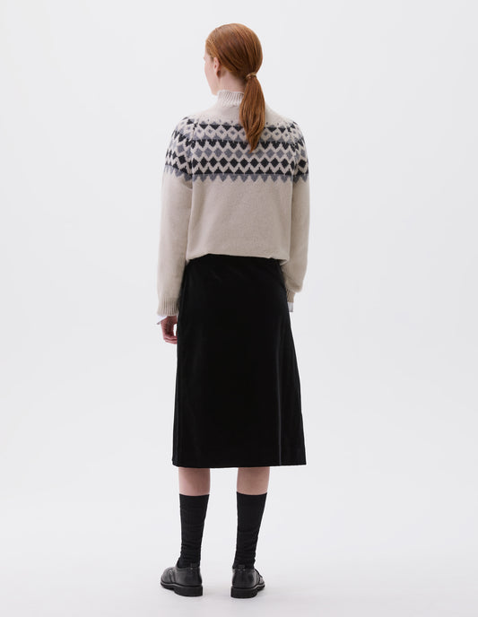 Full body image, back view of model wearing ecru and grey fairisle jumper with inset sleeve and contrasting rib on high neck, cuffs and hem. Styled with black velvet skirt, black socks and black leather brogues. 