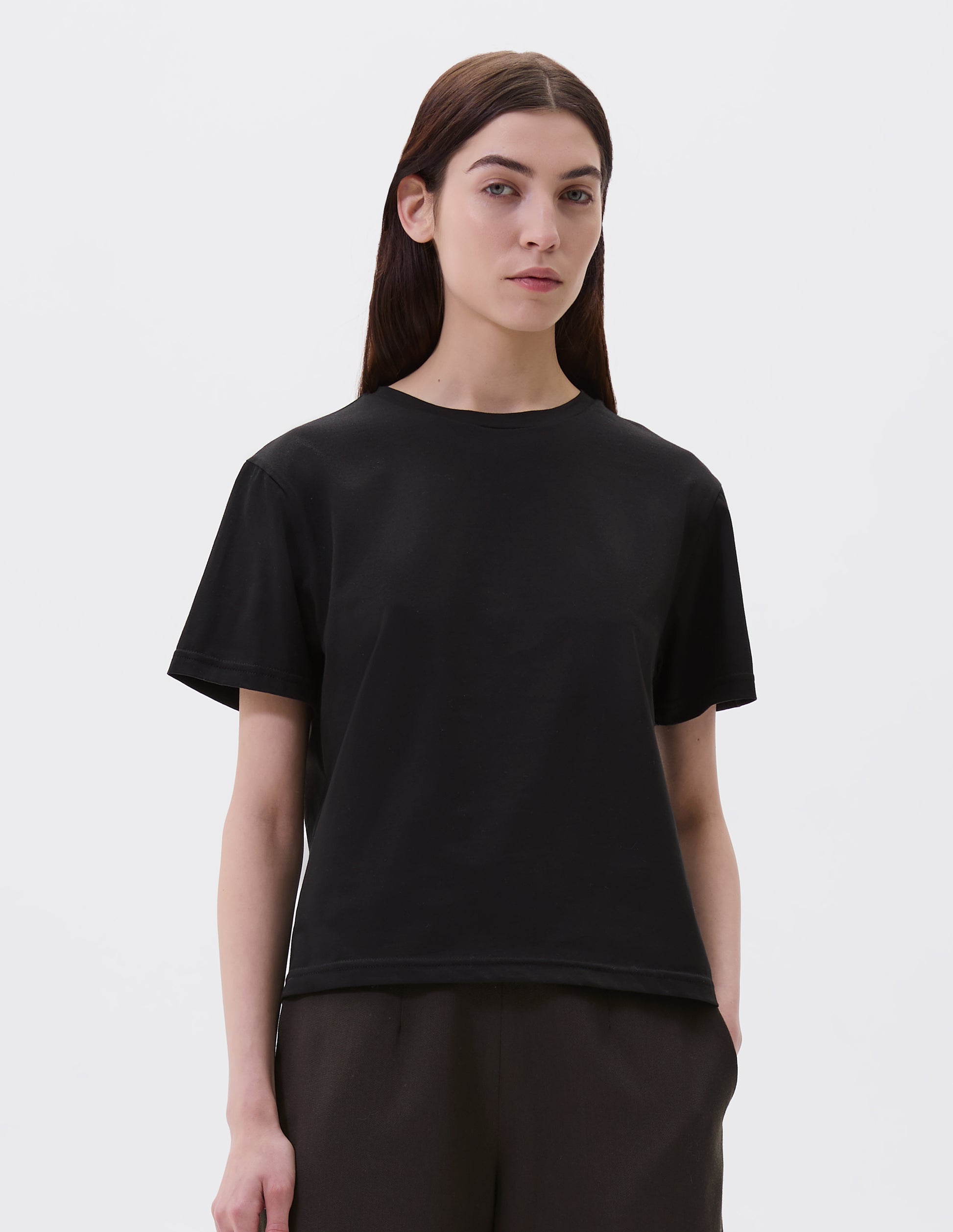 Cropped body image, front view of model wearing black cotton short sleeve t-shirt with boxy cut. Styled with black culottes.