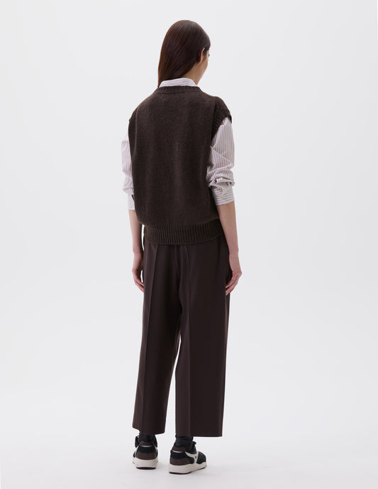 Full body image, back view of model wearing dark brown relaxed boxy slipover with ribbed neck, armhole and hem. Styled with white and pink striped shirt, dark brown trousers and black, brown and white trainers.