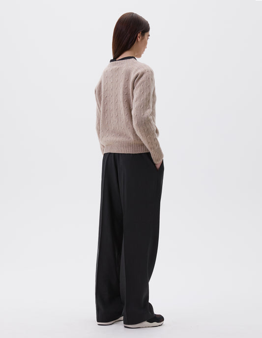 Full body image, back view of model wearing black lightweight trousers with concealed side and back pockets. Styled with black blouse underneath beige cable knit jumper and black and brown trainers.