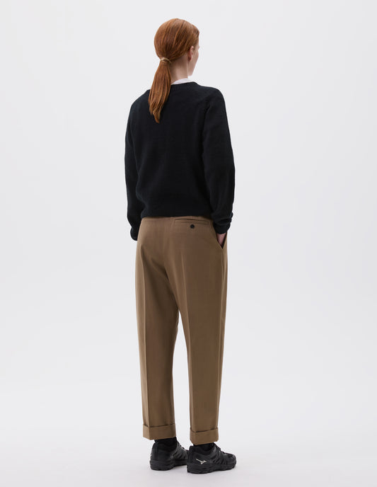 Full body image, back view of model wearing black long sleeve cashmere jumper, with raglan sleeve and contrasting rib on neck, cuffs and hem. Styled over white collared shirt, with brown trousers and black trainers.