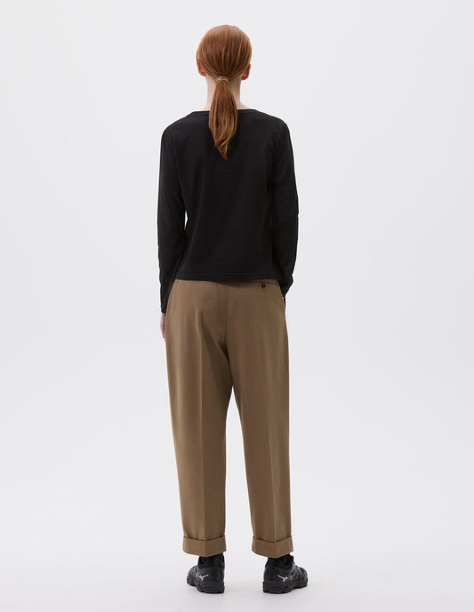 Full body image, back view of model wearing black cotton wide neck long sleeve with boxy cut. Styled with brown trousers and black trainers.