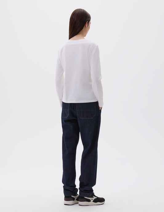 Full body image, back view of model wearing off white cotton wide neck long sleeve with boxy cut. Styled with indigo blue denim jeans and black and brown trainers. 