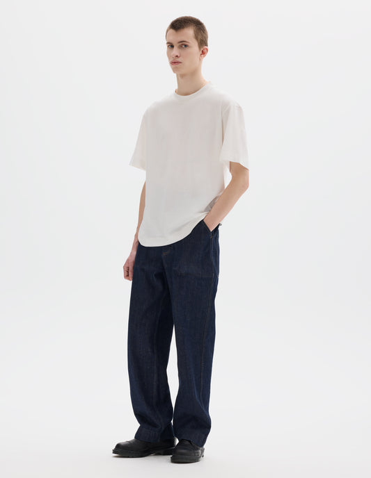 Full body image, front view of model wearing white relaxed cotton t-shirt with crew neck and boxy cut. Styled with dark blue jeans and black leather shoes.