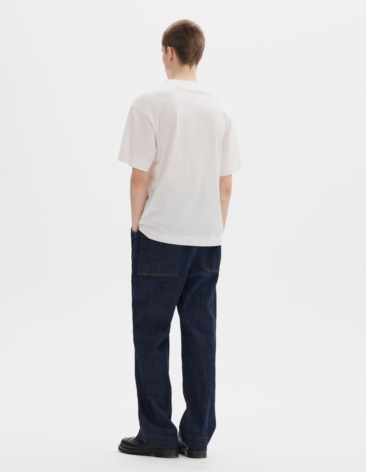 Full body image, back view of model wearing white relaxed cotton t-shirt with crew neck and boxy cut. Styled with dark blue jeans and black leather shoes.