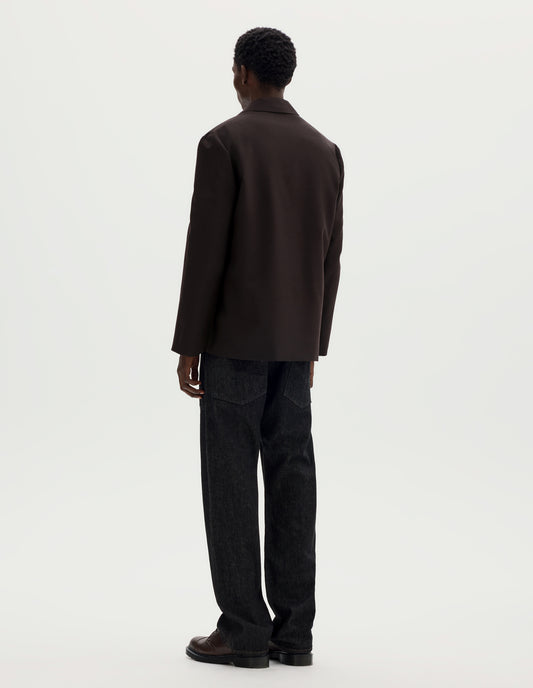 Full body image, back view of model wearing dark brown relaxed wool blazer with dropped shoulders. Styled with black jeans and brown leather shoes.