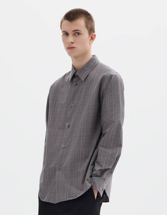Cropped body image, front view of model wearing grey cotton shirt with dark grey and light blue checks, mother of pearl buttons and chest pocket. Styled with black trousers.