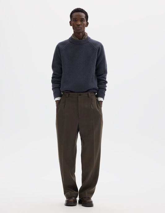 Full body image, front view of model wearing brown straight leg wool trousers with horn button and zip fly fastening, regular belt loops, single pleats, hidden ticket pocket and side pockets. Styled with grey jumper, white shirt, dark beige silk neck scarf and brown leather shoes.