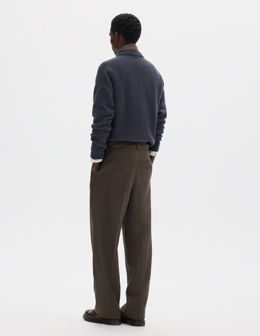 Full body image, back view of model wearing brown straight leg wool trousers with side pockets and horn button-fastening welt back pocket. Styled with grey jumper, white shirt, dark beige silk neck scarf and brown leather shoes.
