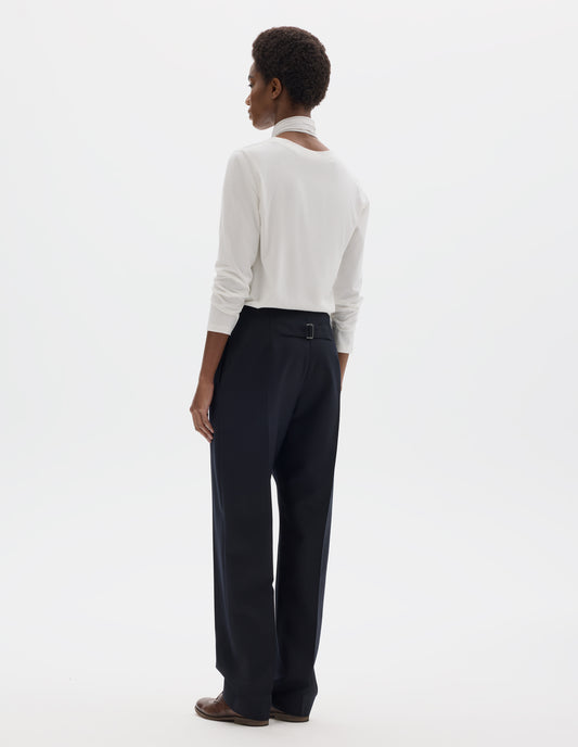 Full body image, back view of model wearing white relaxed cotton t-shirt with wide round neck, long sleeves and boxy cut. Styled with white and blue shirting scarf, dark blue trousers and brown leather brogues.