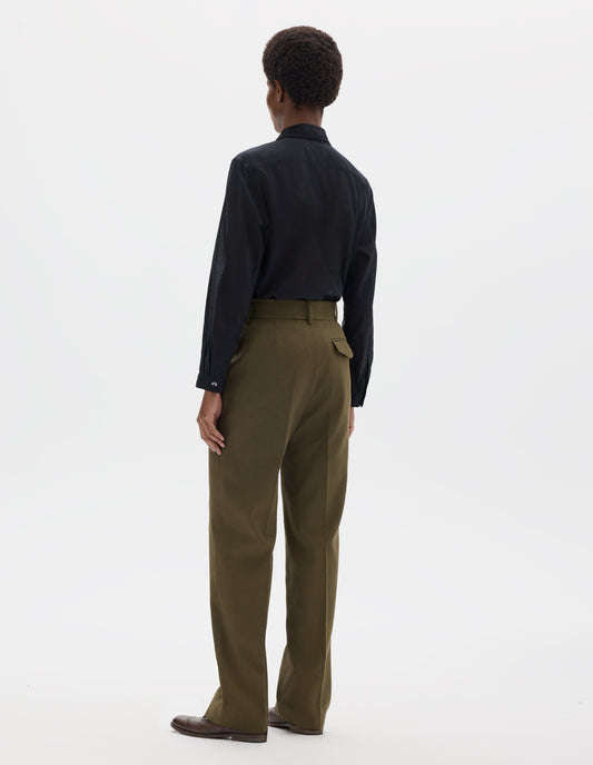 Full body image, back view of model wearing green cotton linen straight leg trousers with belt loops and concealed horn button-fastening flap back pocket. Styled with black shirt and brown leather brogues.