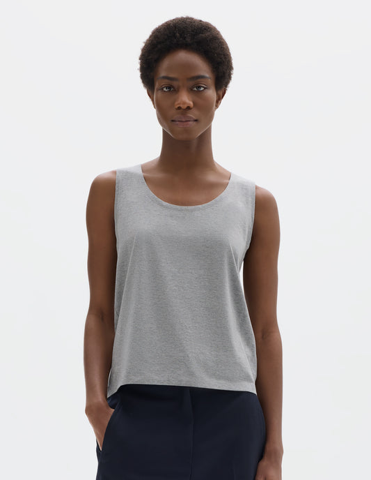 Cropped body image, front view of model wearing grey sleeveless cotton vest with scoop neck. Styled with dark blue trousers.