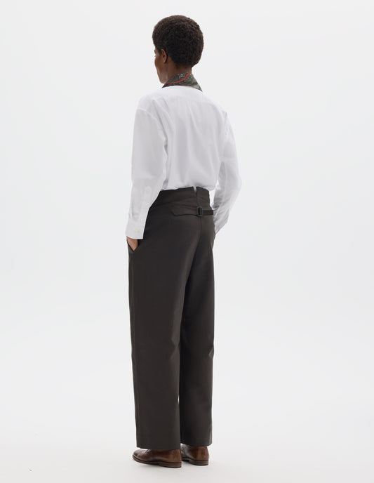 Full body image, back view of model wearing high waisted grey cotton trousers with back cinch. Styled with white shirt, dark green silk scarf and brown leather brogues.