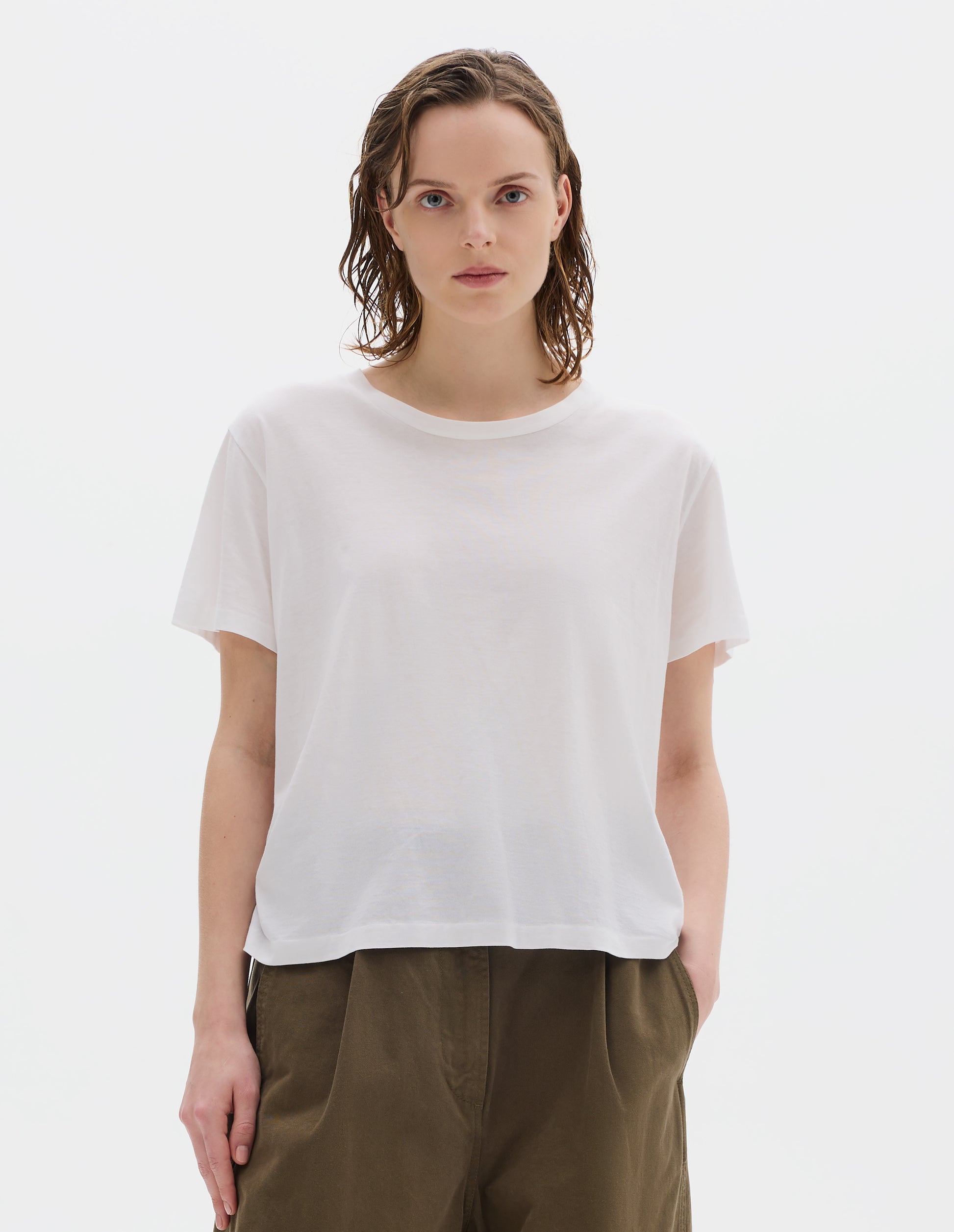 Cropped body image, front view of model wearing white relaxed cotton t-shirt with crew neck and boxy cut. Styled with khaki green trousers.