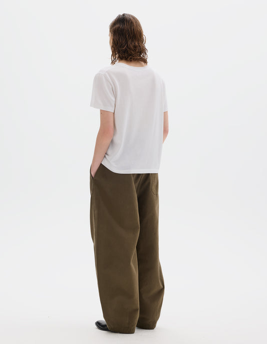 Full body image, back view of model wearing white relaxed cotton t-shirt with crew neck and boxy cut. Styled with khaki green trousers and black leather shoes.