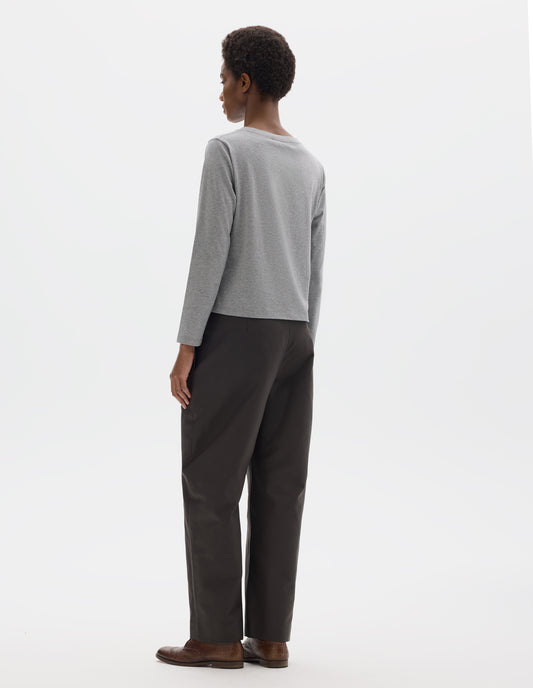 Full body image, back view of model wearing grey relaxed cotton t-shirt with wide round neck, long sleeves and boxy cut. Styled with dark grey trousers and brown leather brogues.