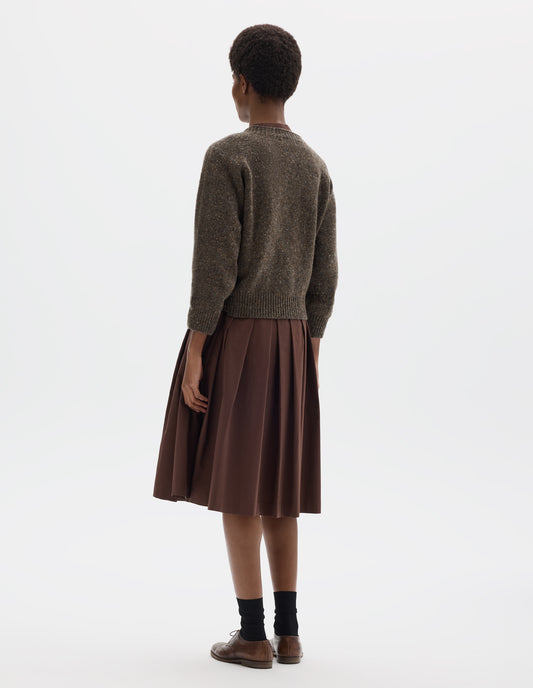 Full body image, back view of model wearing waist length brown crew neck wool jumper with fully fashioned bracelet length raglan sleeves, circular knitted body and wide rib detailing at neck, cuffs and hem. Styled over brown dress, and with black socks and brown leather brogues.