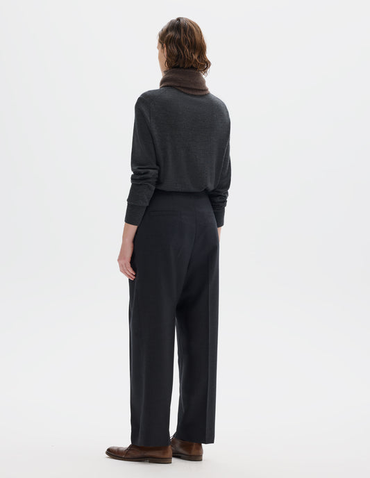 Full body image, back view of model wearing dark grey wool trousers with side cinches and welt back pockets. Styled with brown knitted scarf, dark grey jumper and brown leather brogues.