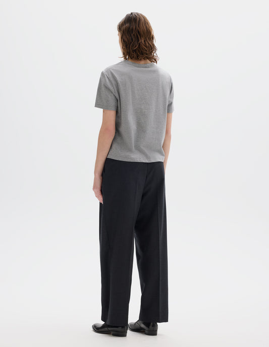Full body image, back view of model wearing grey relaxed cotton t-shirt with crew neck and boxy cut. Styled with dark grey trousers and black leather shoes.