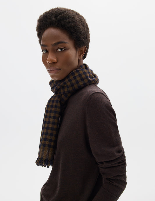 Cropped image, front view of female model wearing brown and dark blue gingham check scarf in wool with frayed edges. Styled with brown brown jumper.