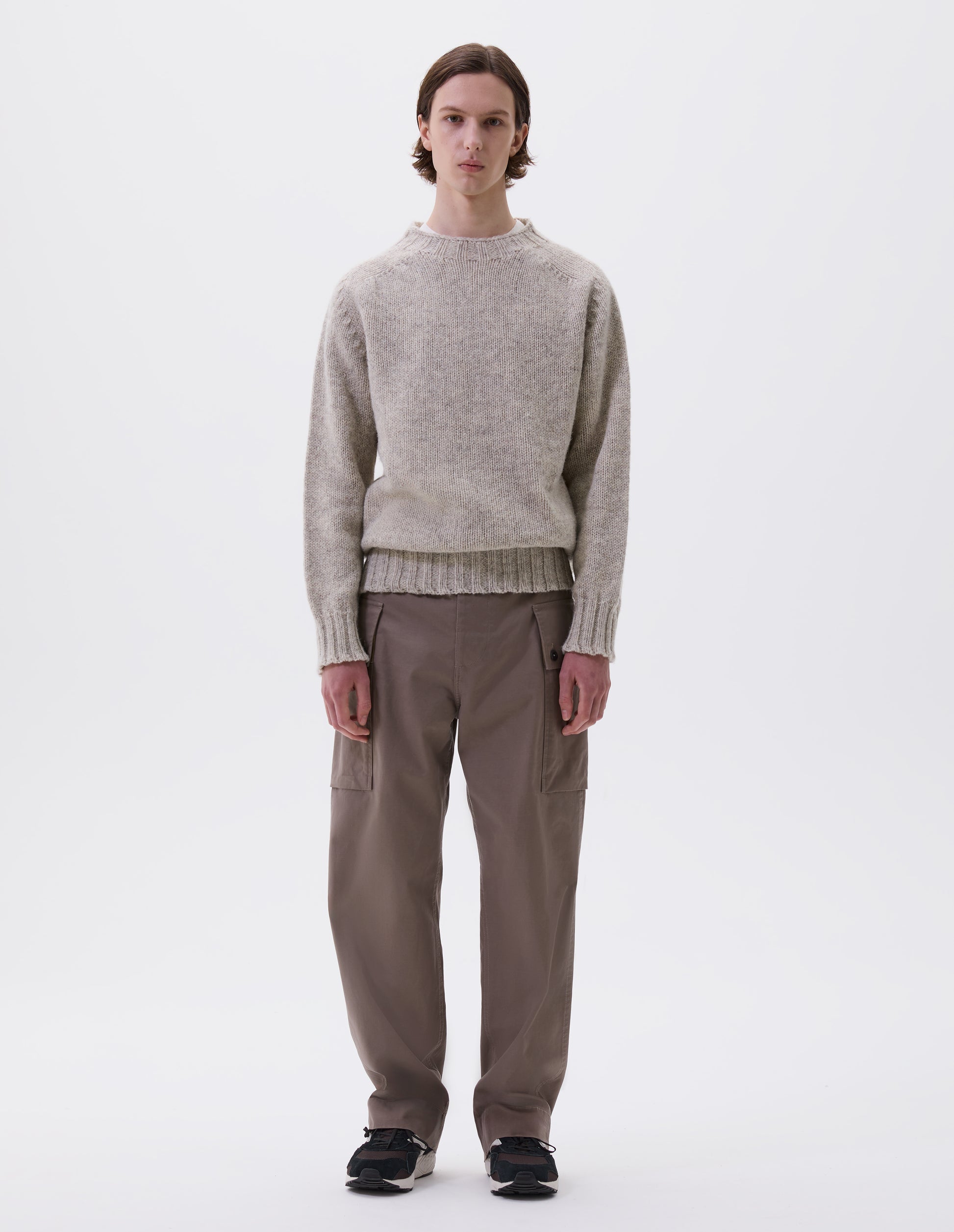 Full body image, front view of model wearing beige marl jumper with saddle sleeves and contrasting rib on neck, cuffs and hem. Styled with beige trousers and black and brown trainers.