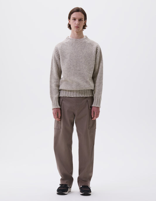 Full body image, front view of model wearing beige marl jumper with saddle sleeves and contrasting rib on neck, cuffs and hem. Styled with beige trousers and black and brown trainers.