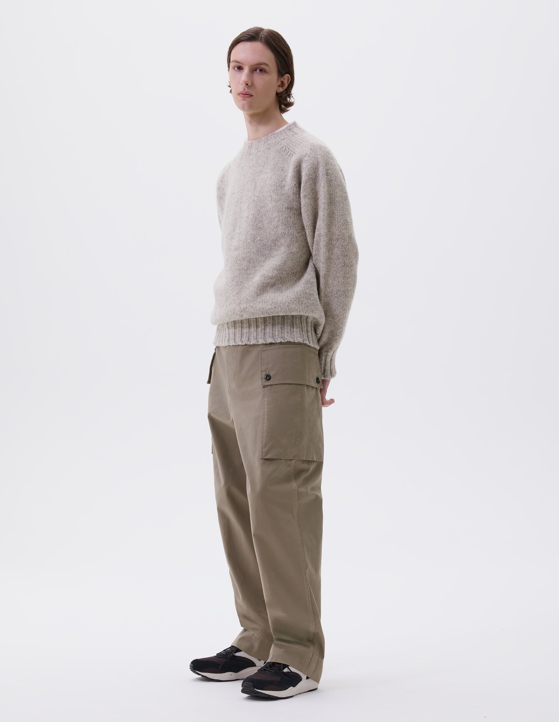 Full body image, front view of model wearing beige cargo trousers with deep flap button fastening patch pocket, concealed hand pockets, belt loops and deep stitch hem. Styled with beige jumper and brown and black trainers.
