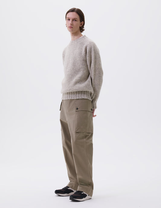 Full body image, front view of model wearing beige cargo trousers with deep flap button fastening patch pocket, concealed hand pockets, belt loops and deep stitch hem. Styled with beige jumper and brown and black trainers.
