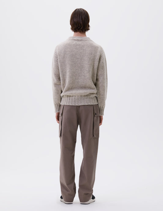 Full body image, back view of model wearing beige marl jumper with saddle sleeves and contrasting rib on neck, cuffs and hem. Styled with beige trousers and black and brown trainers.
