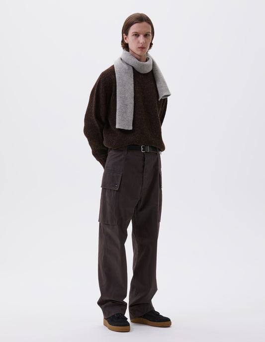 Full body image, front view of model wearing brown cargo trousers with deep flap button fastening patch pocket, concealed hand pockets, belt loops and deep stitch hem. Styled with brown jumper, grey scarf, black leather belt and black suede trainers.
