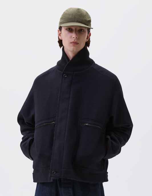 Cropped body image, front view of male model wearing khaki green soft peak cap with contrast herringbone tape slide adjustor detailing. Styled with navy blue ribbed neck jacket and indigo blue jeans.