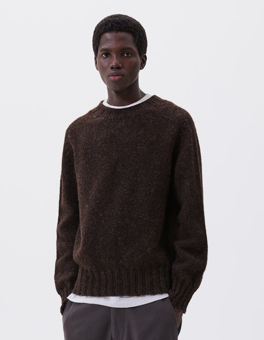 Cropped body image, front view of model wearing dark brown marl jumper with saddle sleeves and contrasting rib on neck, cuffs and hem. Styled over white t-shirt, with grey trousers.