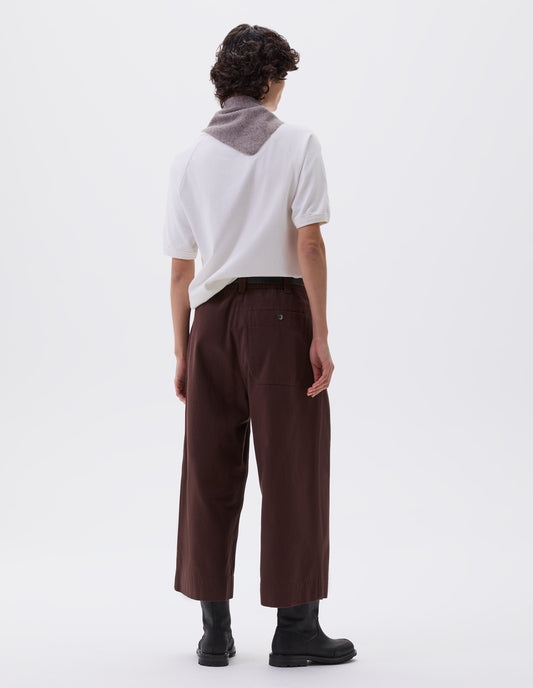Full body image, back view of model wearing red brown culottes with half elasticated waist, belt loops and press stud patch back pocket. Styled with white t-shirt, grey scout scarf and black leather boots.