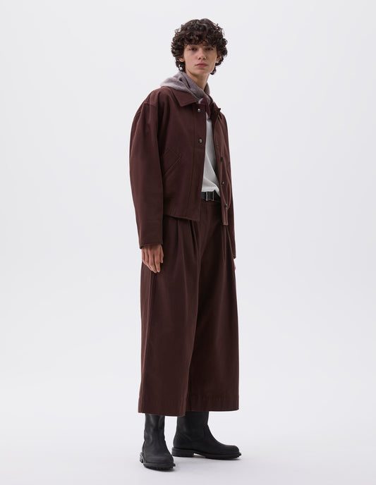 Full body image, front view of model wearing red brown collared jacket with press stud closure, slant deep welt pockets and ribbed hem. Styled with matching culottes, white t-shirt, grey knitted scout scarf, black leather belt and black leather boots. 