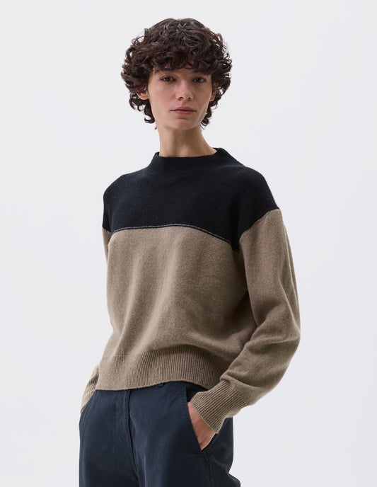 Cropped image, front view of model wearing cropped black and beige jumper with ribbed crew neck, cuffs and hem. Styled with black trousers.